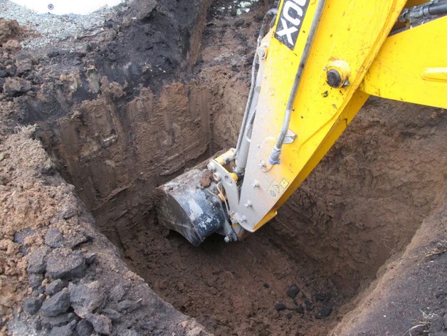 Экскаватор роет яму под колодец